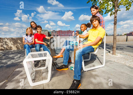 Positive Kinder sitzen auf weißen Stühlen mit skateboards Stockfoto