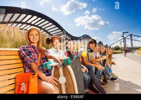 Gruppe von Kindern zusammensitzen auf Holzbank Stockfoto