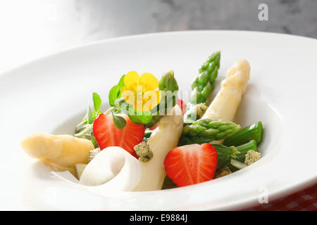 Salat frisch gewürfelte Spargelspitzen und Erdbeeren in eine schlichte weiße Schale serviert Stockfoto