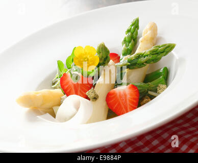 Salat frisch gewürfelte Spargelspitzen und Erdbeeren in eine schlichte weiße Schale serviert Stockfoto