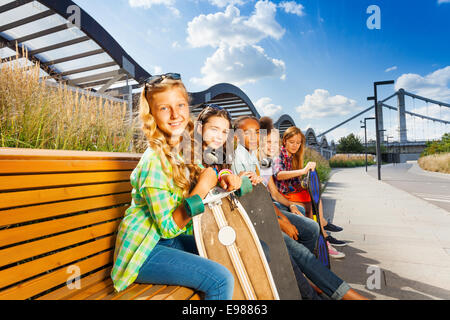 Kinder sitzen auf Bank im Sommer mit skateboards Stockfoto