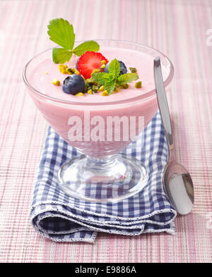 Erdbeer-Pudding in eine Schüssel geben. Stehend auf einer Serviette auf rosa Hintergrund. Stockfoto