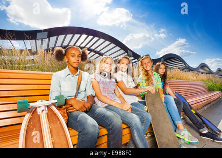 Schöne Mädchen mit Skateboards sitzen auf Bank Stockfoto