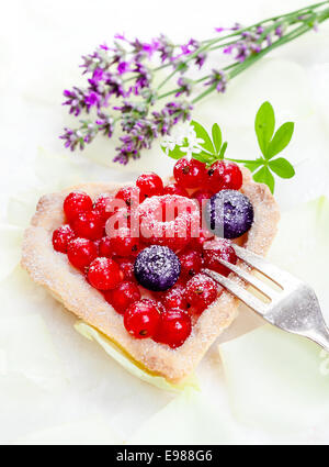 Herzförmige Johannisbeer Törtchen mit ganzen Früchten mit Zucker gefrostet und serviert mit einer silbernen Kuchengabel Stockfoto