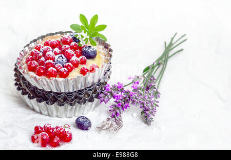 Recurrant Herb Stillleben mit eine frisch gebackene Torte mit ganzen Beeren balanciert auf einem Haufen geriffelte dekorative Metall-Torte Pfannen neben frischem Lavendel Stockfoto