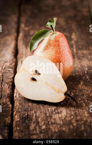 Halbierte frische saftige Birne gegen eine ganze Frucht auf der Spitze eines groben Holztisch abgewogen Stockfoto