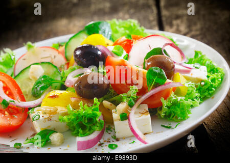 Detailansicht der einen Teller mit frischen gesunden griechischer Salat mit Kopfsalat, Basilikum, Schafskäse, Zwiebeln, Oliven, Radieschen und Tomaten Stockfoto