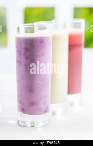 Ein großes Glas cremig gemischt Joghurt-Beeren-Smoothie mit einer Vielzahl von anderen Geschmacksrichtungen zurückweichenden hintereinander mit flachen dof Stockfoto