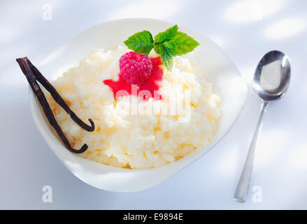 Eine Portion leckere Milchreis mit Milch oder Sahne zubereitet und garniert mit Himbeer-Vanille Schoten Stockfoto