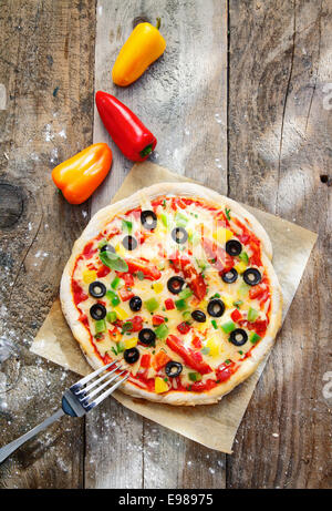 Draufsicht auf eine leckere bunte selbstgebackenen Pizza mit eine dicke Kruste und belegt mit Käse, Paprika, Tomaten und Oliven Stockfoto