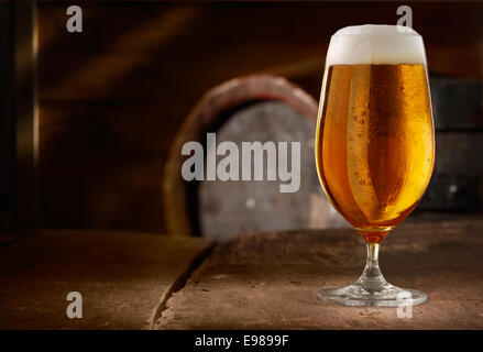 Nahaufnahme von einem Glas frisch schäumende Bier auf einem Tisch in einem Vintage Bierkeller Stockfoto