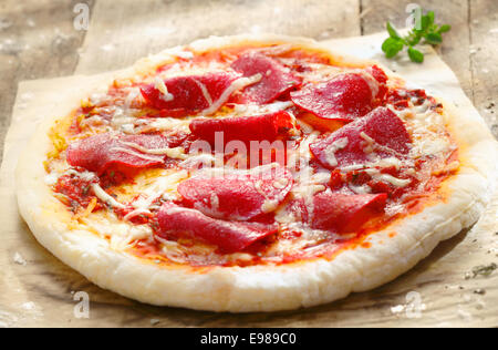 Pizza Diavolo mit Salami Fleisch und Rot-heiße Paprika auf einem rustikalen Tisch in eine Pizzeria, italienische Küche-Konzept Stockfoto