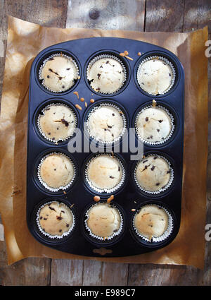 Draufsicht auf ein Backblech mit frisch gebackenen Muffins aus dem Ofen nehmen, abkühlen auf eine alte hölzerne Oberfläche Stockfoto