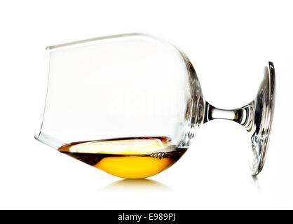 Leuchtenden goldenen Cognac oder Weinbrand in einem Cognac-Schwenker Glas liegend auf einem weißen Hintergrund Stockfoto