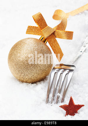 Glänzend Silber Weihnachten Gabel und ornamentalen Goldglitter Christbaumkugel mit einem Stern in weichen weißen Winterschnee Stockfoto