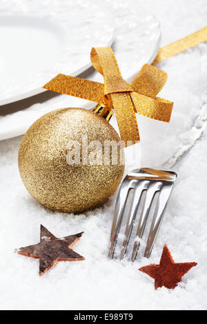 Weihnachten Winter Gedeck auf Schnee mit Silberbesteck dekoriert mit einer goldenen Kugel und Sternen Stockfoto