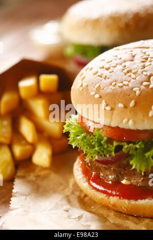 Zwei Hamburger und Pommes Frites mit Sesam Brötchen auf braunem Papier. selektiven Fokus Stockfoto