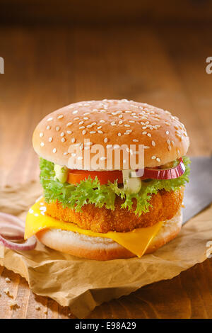 Leckere Hähnchen Burger mit einer goldenen Panierter Patty und Salat Zutaten auf trashigen zerknitterten braunem Papier aus Holz im Hintergrund mit Exemplar Stockfoto