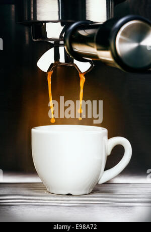 Nahaufnahme einer professionellen Edelstahl Kaffee Maschine Gießen frisch gebraut in eine schlichte weiße Keramik Tasse aromatischen Espresso-Kaffeemaschine Stockfoto