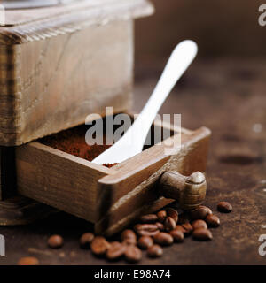 Frisch gemahlener Kaffee und einem Messlöffel in die geöffnete Schublade einen alten Retro-hölzernen Schleifer Stockfoto