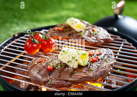 Saftige Portion mageres Steak, garniert mit Butter und Kräutern auf einem Gitter über glühende Kohlen in einem Grill Grillen Stockfoto