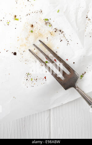Alte Küche Gabel ruht auf gefärbten weißes Papier mit zerstreuten Überreste würzen und Gewürze auf einem weißen Holzbrett-Hintergrund Stockfoto