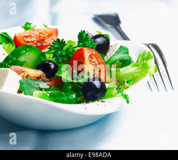 Knackig frische griechischer Salat mit Fetakäse, Oliven, Blattgemüse und Tomaten garniert mit Petersilie Stockfoto