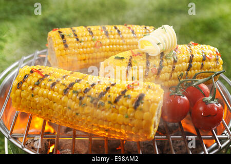 Gesunde vegetarische Grill mit reif goldene Mais Maiskolben und saftige rote Kirschtomaten, über dem Feuer Grillen im Freien auf einer Stockfoto