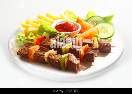 Drei gegrillte Rindfleisch und Paprika Kebab serviert auf einem einfachen weißen Teller mit Pommes frites, Tomaten-Ketchup und gemischtem Salat auf einem Stockfoto