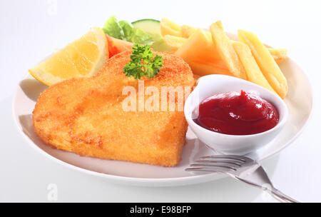 Golden gebratenen Schnitzel oder Schnitzel in Paniermehl mit einer Beilage von Ketchup oder Tomaten-Sauce, serviert mit einer Scheibe Zitrone und Pommes frites Stockfoto