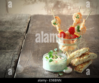 Leckere Garnelen oder Shrimps Vorspeisen mit Tomaten am Spieß serviert mit Tartar-Sauce und frisch gebackene italienische Focaccia-Brot Stockfoto