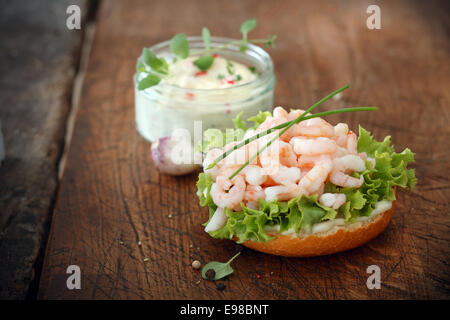 Gourmet-Garnelen Bruschetta, eine italienische Antipasti, auf einem Bett aus frischem grünen Salat auf geröstetem Baguette serviert mit einem Glas Tartare Sauce Stockfoto