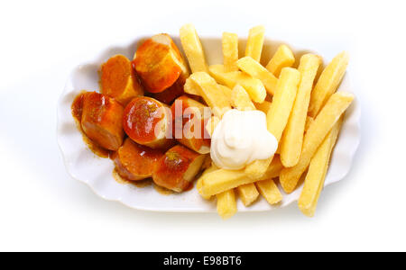 Scheiben vom geräucherten Bratwürste und knusprig goldene Pommes Frites mit Mayonnaise in eine geriffelte weiße Schale, über den Kopf Blick auf gekrönt Stockfoto