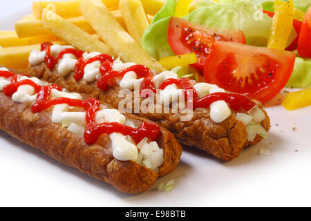 Dekorative würzige Kaminwurzen garniert mit Mayonnaise und Ketchup mit frischem Salat und goldene Pommes frites Stockfoto