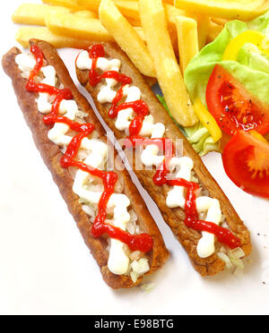 Zwei köstliche hausgemachte Frikandel, Netherland Spezialitäten mit dekorativen Mayonnaise und Ketchup Tomatensoße mit frischem Salat und Tomaten und gebratenen goldene Kartoffel-Chips, Ansicht von oben Stockfoto