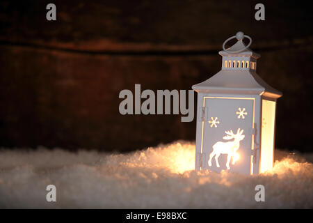 Weihnachten Laterne mit einer dekorativen ausgeschnittene Muster von einem Rentier stehend auf einem Bett aus frischen Winterschnee Leuchten in der Nacht als ein einladendes Licht mit Exemplar für Ihre saisonalen Gruß Stockfoto