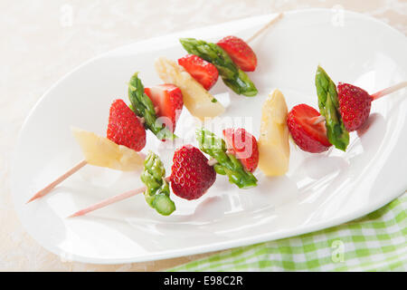 Spargel und Erdbeeren Vorspeise mit frischem grünen und weißen Spargelspitzen gekocht und in Scheiben geschnitten Reife rote Erdbeeren am Spieß Stockfoto