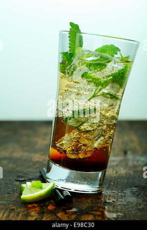 Geeiste Mojito cocktail mit Rum und Minze serviert in ein hohes Glas auf eine alte hölzerne Tabelle oder Bar Theke Stockfoto