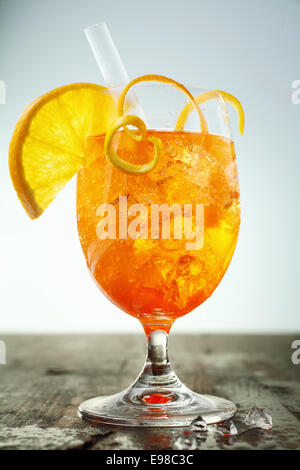 Bunte Eistee Rum und Orange cocktail garniert mit Orangenscheiben und Rinde stehen auf einem hölzernen Theke mit Auslaufen am Fuße Stockfoto