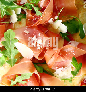 Köstliche italienische dünn geschnittenen Schinken und Rucola Blätter diente als Topping auf eine Pizza, Closeup Erstansicht Stockfoto