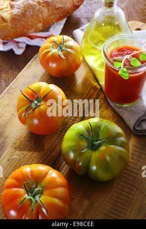 Zubereitung frische Tomatenmark für die Verwendung als Zutat in der italienischen Küche mit frischen, ganzen Tomaten und Olivenöl auf einem hölzernen Küchentisch Stockfoto