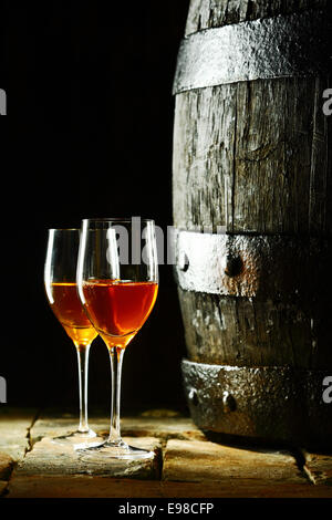 Alte Eiche Weinfass mit zwei Gläser Rotwein vor einem dunklen Hintergrund erinnert an einen Keller in einem Weingut Stockfoto