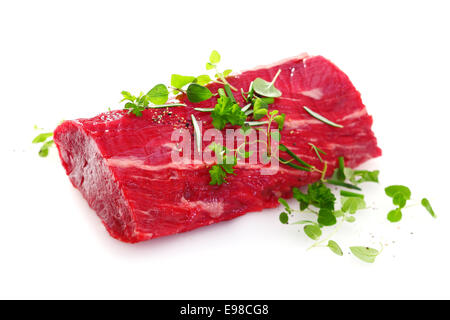 Saftige Portion mageres rohem Filetsteak für ein gesundes rotes Fleisch essen, garniert mit frischen grünen Kräutern auf weißem Hintergrund Stockfoto