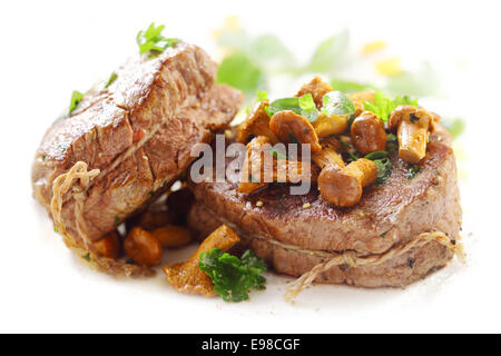 Zwei saftige Dicke gegrillte Medaillons vom Filet mit Schnur gebunden und garniert mit gebratenen Champignons auf einem weißen Teller serviert Stockfoto