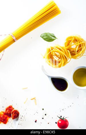 Zutaten für das Kochen Spaghetti und Fettucini verstreut auf einem weißen Hintergrund mit Copysace mit frischen Tomaten und Tomatenmark Stockfoto