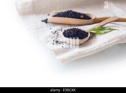 Frisch getrocknet Lose-Blatt-Tee in einem kleinen hölzernen Löffel mit einem frischen Teeblatt mit Exemplar Stockfoto