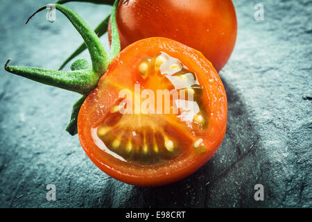 Nahaufnahme einer halbierten saftig frische Trauben Tomate zeigt die Kerne und das Fruchtfleisch mit einem grünen Stiel für einen gesunden Salat oder Kochzutat Stockfoto