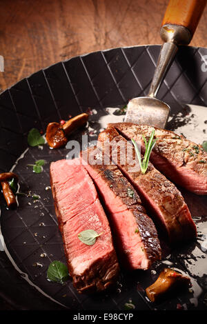 Selten gekochtes mageres Rindfleischsteak oder Filet geschnitten durch in einem Bräter während des Kochen und Vorbereitung einer Gourmet-Mahlzeit Stockfoto