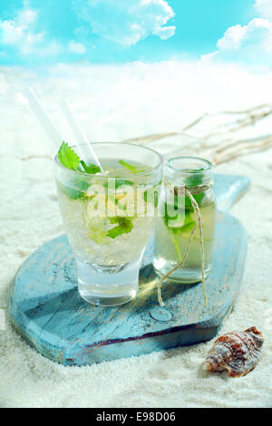 Erfrischenden Mojito cocktail am Meer an einem tropischen Strand auf einem alten Holzbrett serviert Stockfoto