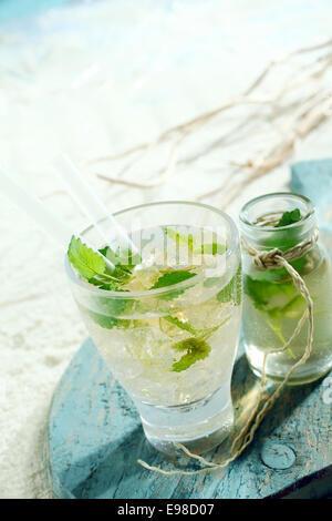 Eis kalt Mojito cocktail mit würzigen Limetten und Minze serviert in einem Glas mit einer begleitenden Karaffe Stockfoto